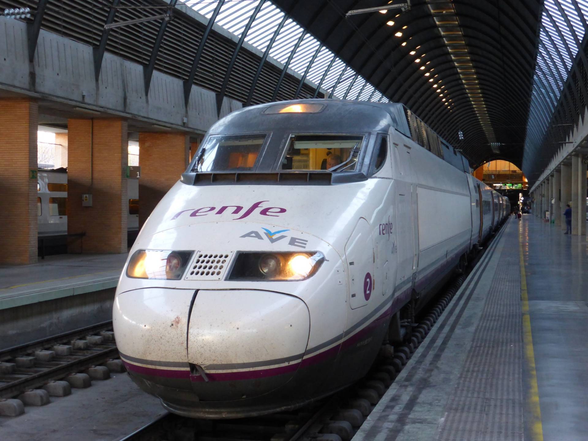 A Renfe AVE Series 100 train at a platform under the arched roof of Sevilla Santa Justa station