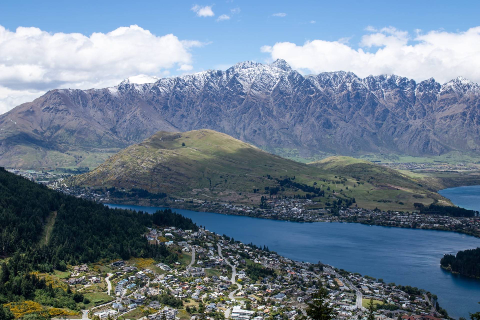 Queenstown suburbs and the Frankton Arm of Lake Wakatipu seen from above, with the snow-dusted Remarkables range behind