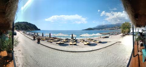 Sun umbrellas and loungers on Potami beach beside the promenade and blue sea
