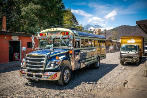 A brightly painted and chromed former school bus parked on a cobbled street in Antigua Guatemala with a hill behind