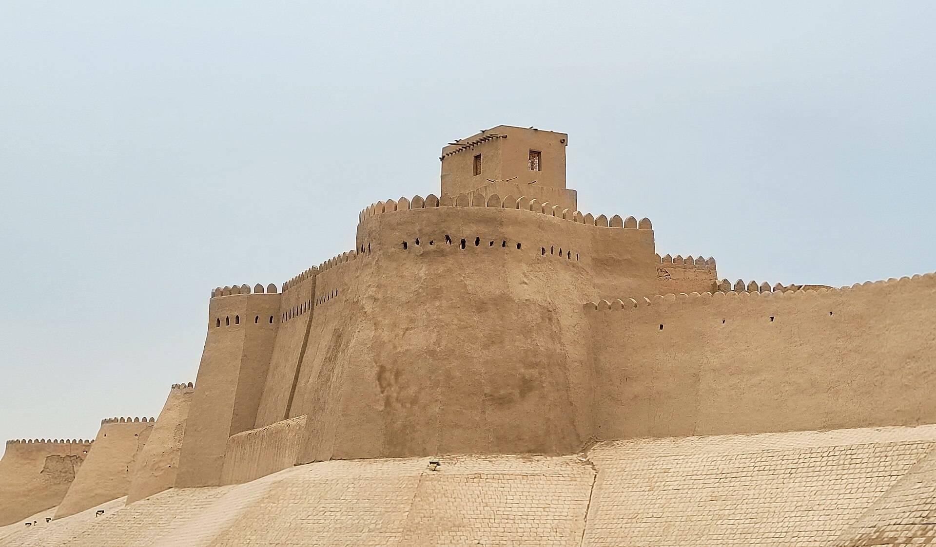 Earthen walls and a tower of Itchan Kala in Khiva beneath a pale sky